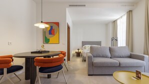 A modern hotel room with a dining area, a sofa, and a bed.