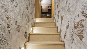 Un escalier étroit, agrémenté de motifs décoratifs sur les murs, mène à une cuisine.