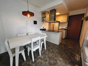 Kitchen area with central island, dining table, and pendant light, featuring an oven and range hood.