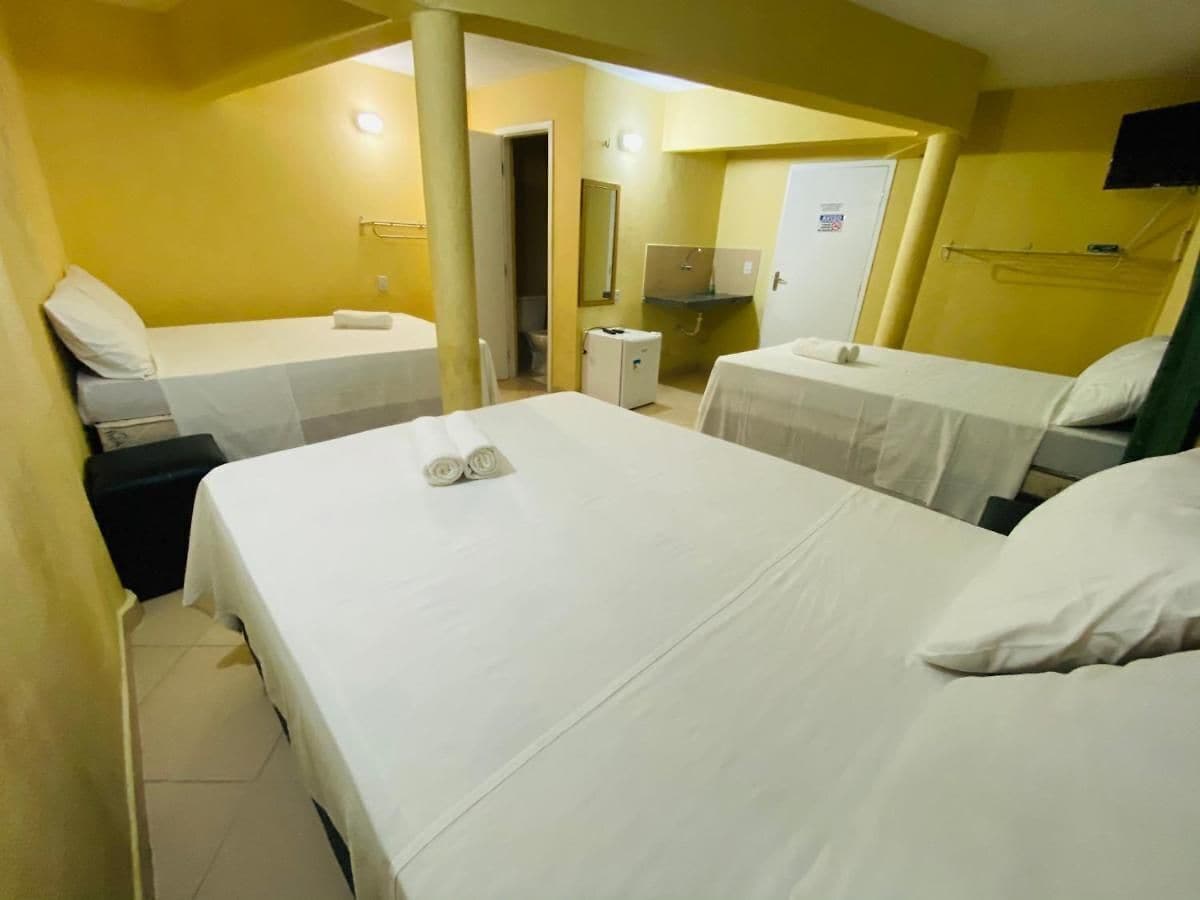 A hotel room with two single beds, a small bedside table, a mirror, and a door leading to a bathroom.