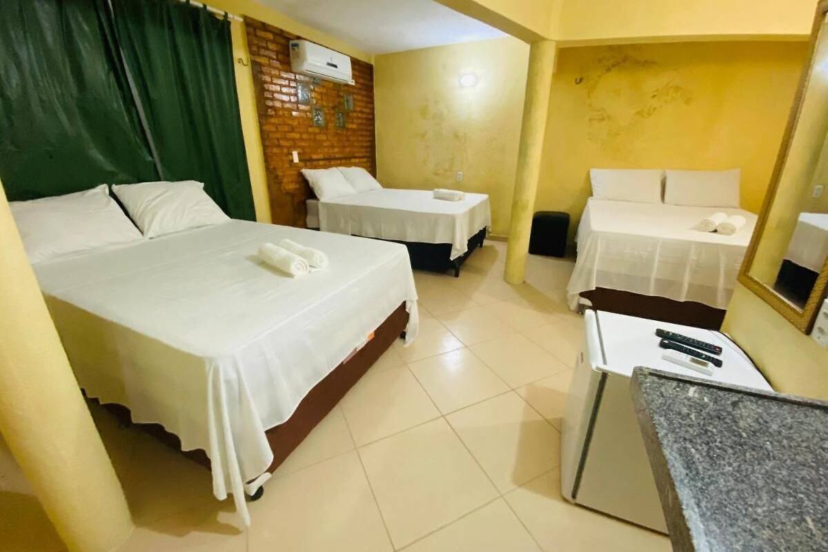 A hotel room with two beds, a small desk, and a mirror.
