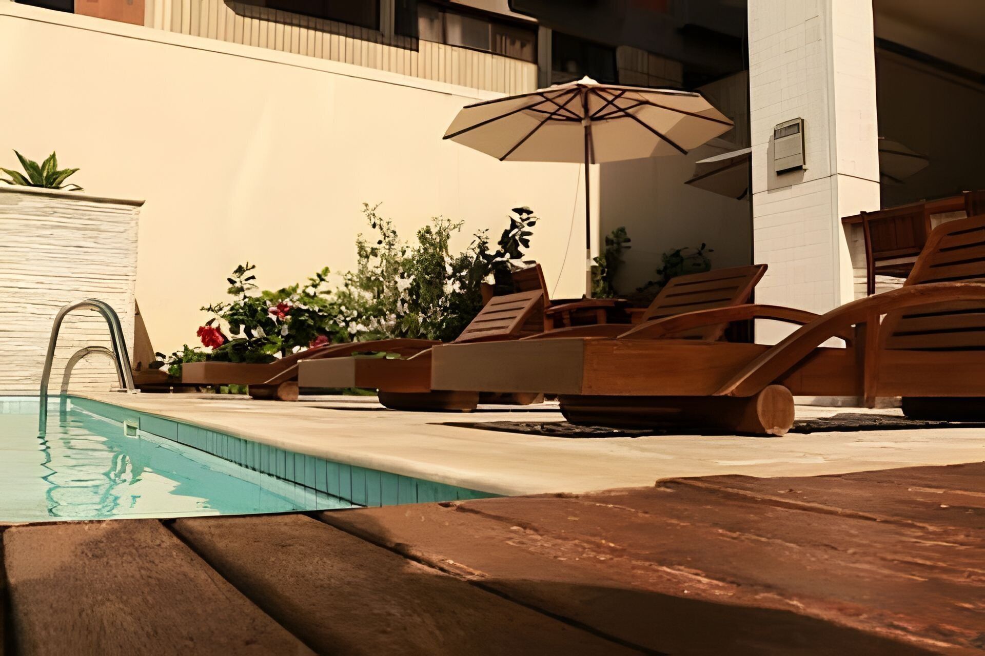 A pool area with lounge chairs and an umbrella.