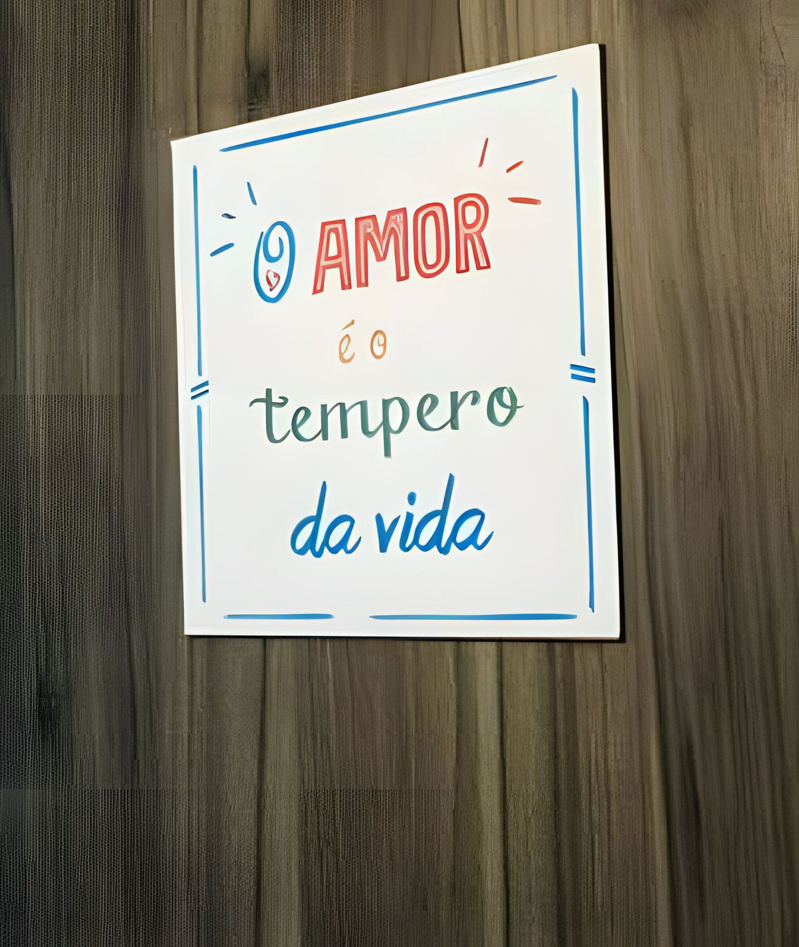 Un cartello con la scritta 'AMOR é o tempero da vida' su sfondo di legno.