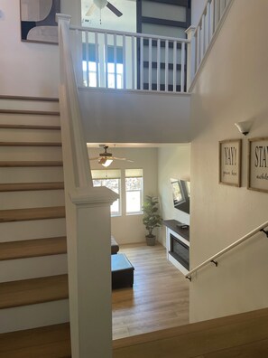 A staircase leading to a second floor with a ceiling fan, a potted plant, and a wall with two framed motivational quotes. - Charming and recently upgraded  3-bedroom townhome with AC in Flagstaff. (Flagstaff)
