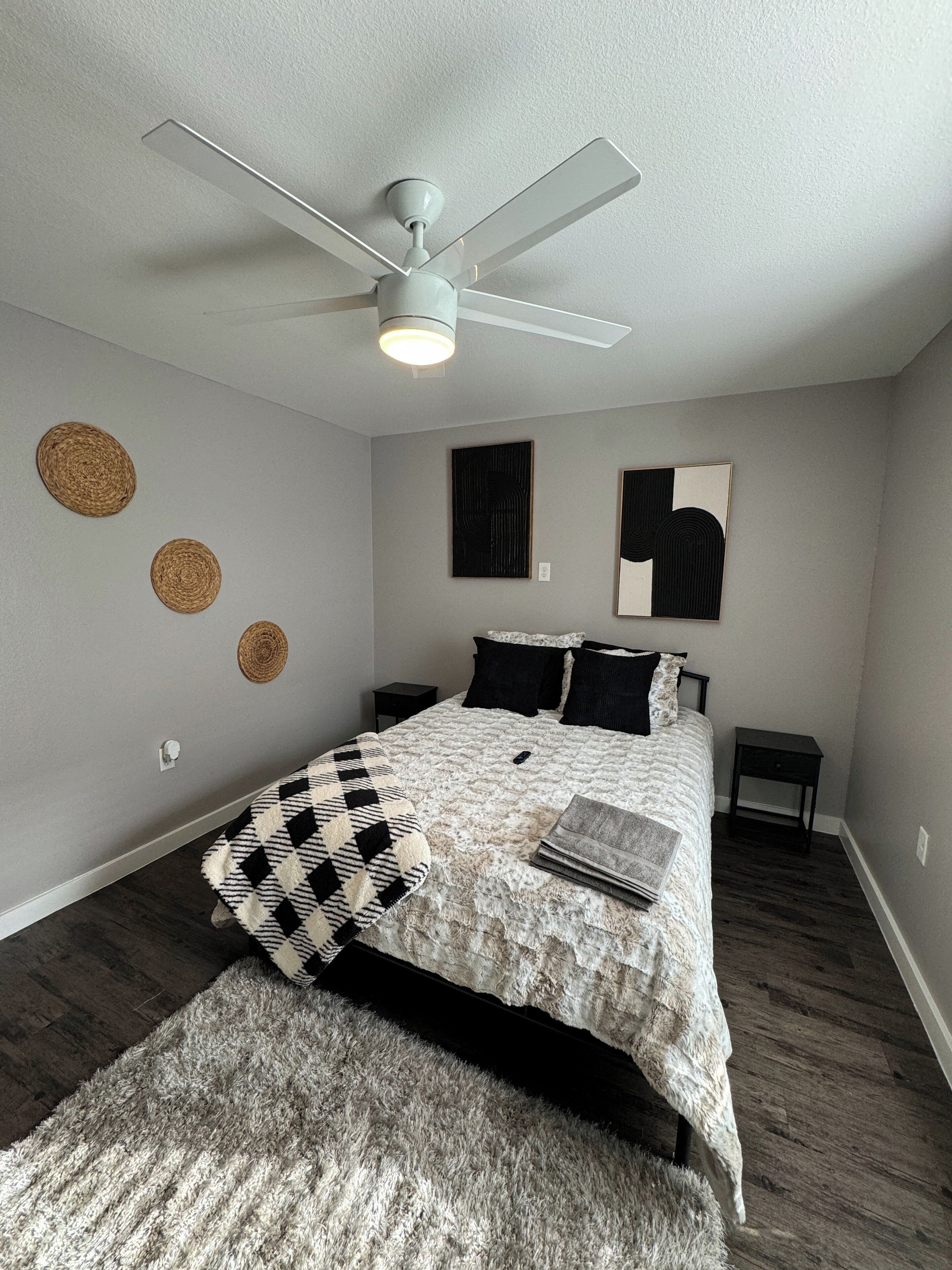 Ein Schlafzimmer mit einem Bett, einem Deckenventilator und einem Teppich.