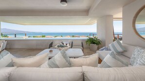 Un balcón amplio con vistas al mar, amueblado con un sofá, sillas y una mesa.