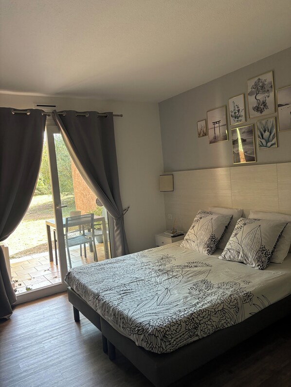 A bedroom with a bed, curtains, a chair, and a table.