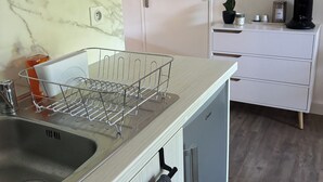 A kitchen with a marble backsplash, a sink with a dish rack, a white cabinet, and a coffee machine. - Studio 1 room + pools  (Arles)