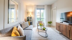 A modern living room with a grey sofa, a coffee table, a TV, and a wooden cabinet. - Luxury Apartment with Elevator and Private Parking (Lucca)