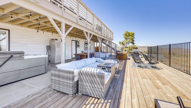 A wooden deck with outdoor seating, including a sofa and chairs, and a grill area. - High-Desert Home w/ Hot Tub & Cowboy Pool (Joshua Tree)