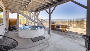An outdoor patio with a hot tub, seating area, and a view of the desert. - High-Desert Home w/ Hot Tub & Cowboy Pool (Joshua Tree)