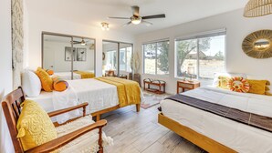 A bedroom with two beds, a ceiling fan, large windows, and a view of the outside. - High-Desert Home w/ Hot Tub & Cowboy Pool (Joshua Tree)