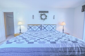 Quarto com cama, duas luminárias de cabeceira, uma placa na parede com a inscrição 'Bed Chamber' e uma guirlanda.