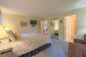 A bedroom with a bed, a TV mounted on the wall, a door leading to another room, and a mirror on the wall. - Official Seasons RMC Condo 02F - 1 bedroom + loft - sleeps 8 - No Fees (Bartlett)