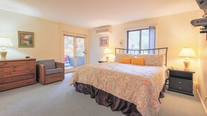 A bedroom with a bed, a chair, a dresser, a nightstand, and a window.