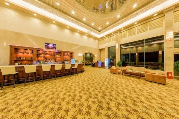 A hotel lobby with a bar area, seating, and a patterned carpet.