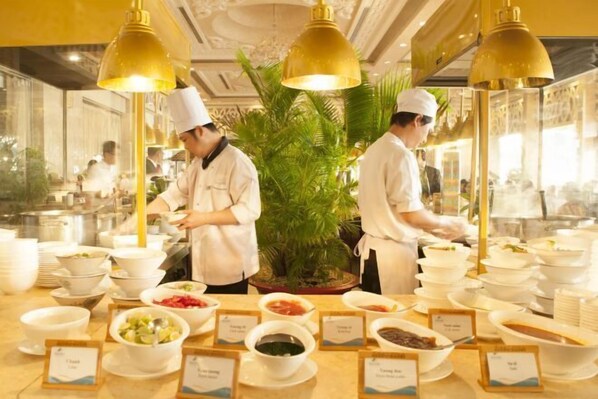 A buffet setup with multiple food stations, each labeled with the type of food served. - Sea Links Beach Villa (Phan Thiet)