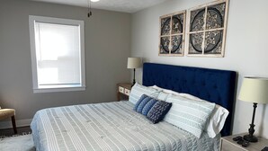 Un dormitorio con una cama grande, una mesita de noche, una lámpara y decoración en la pared.