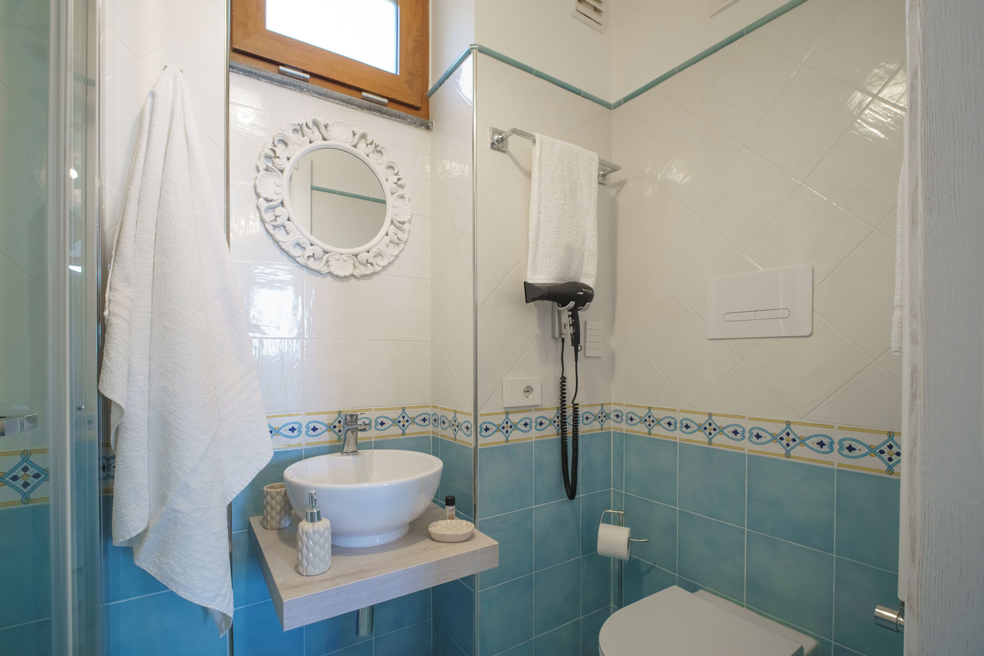A bathroom with a glass shower enclosure, a white sink, a mirror, and a towel rack.