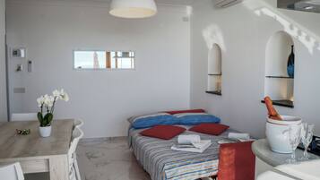 Une chambre à coucher avec un lit, des oreillers, une table de chevet, un vase et une bouteille.