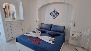 A bedroom with a bed, dresser, nightstands, and a chandelier.