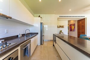 Una cocina moderna con armarios blancos, un refrigerador de acero inoxidable y una encimera oscura.