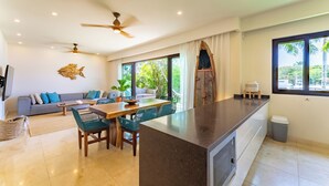 A modern living room with a sofa, dining table, chairs, and a ceiling fan. - Ground Floor Marina View Infinity Pool Private Terrace Puerto Aventuras (Puerto Aventuras)