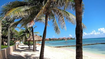 Praia particular, areia branca, espreguiçadeiras, guarda-sóis