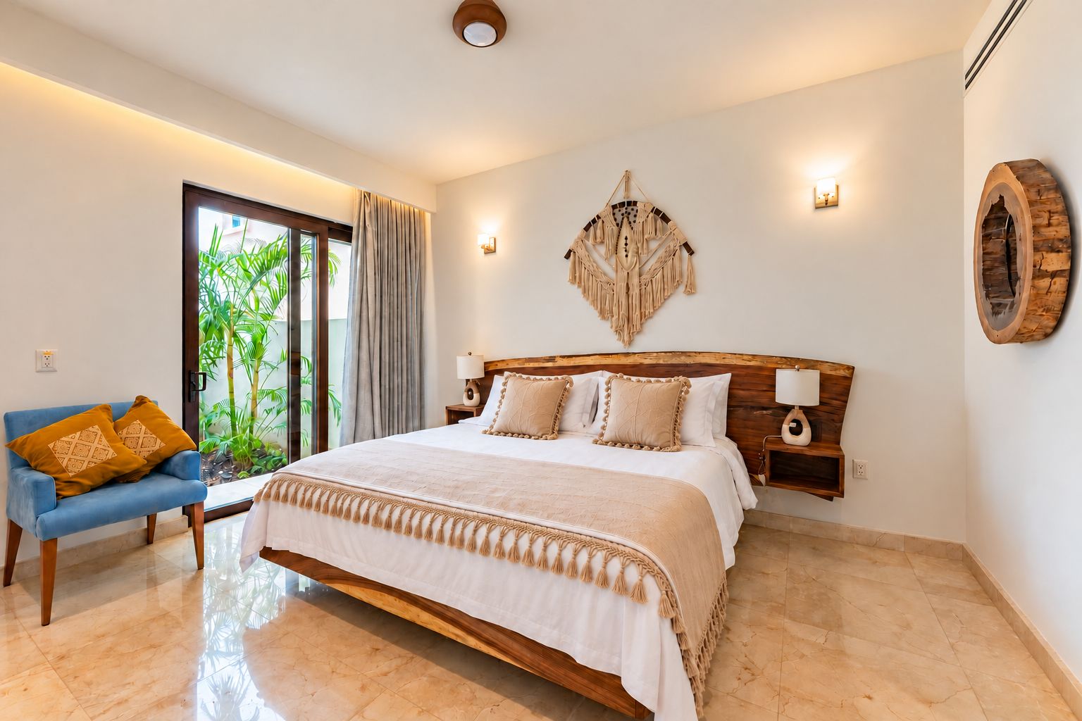 A bedroom with a large bed, a blue chair, and a view of greenery outside.