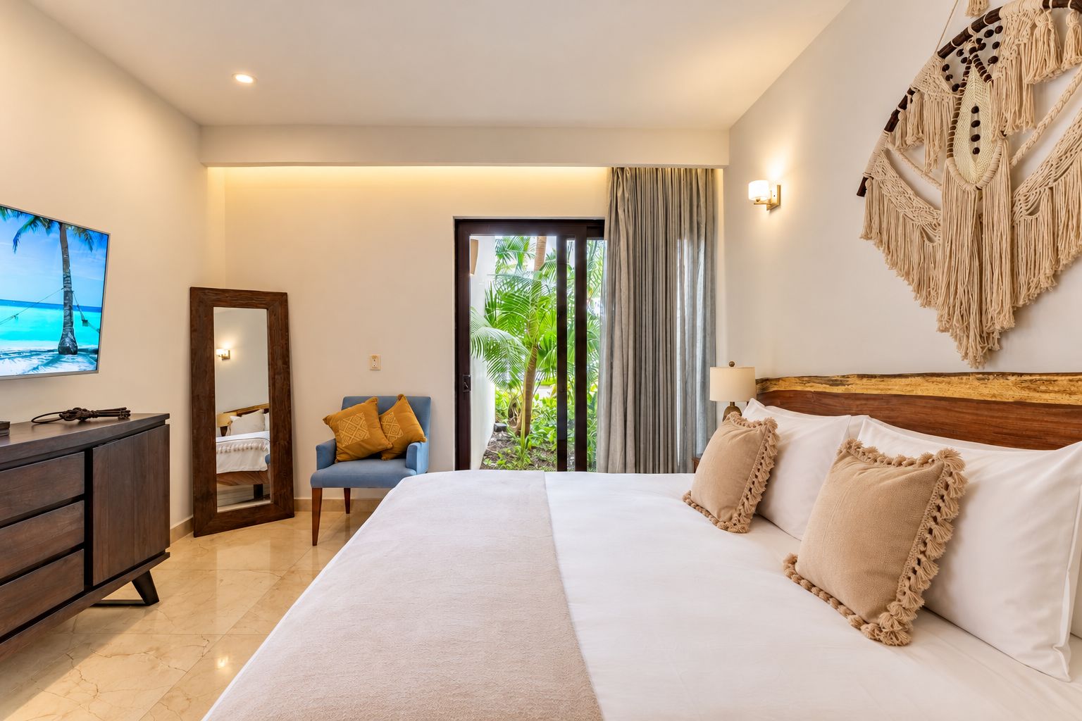 Une chambre d’hôtel avec un lit, un bureau, une chaise, une télévision et une vue sur la verdure par la fenêtre.