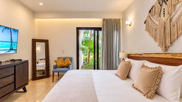Habitación de hotel con cama, escritorio, silla, televisor y vista a zonas verdes a través de una ventana.