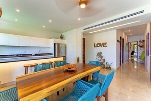 Una cocina moderna con armarios blancos, una mesa de comedor de madera y sillas azules.