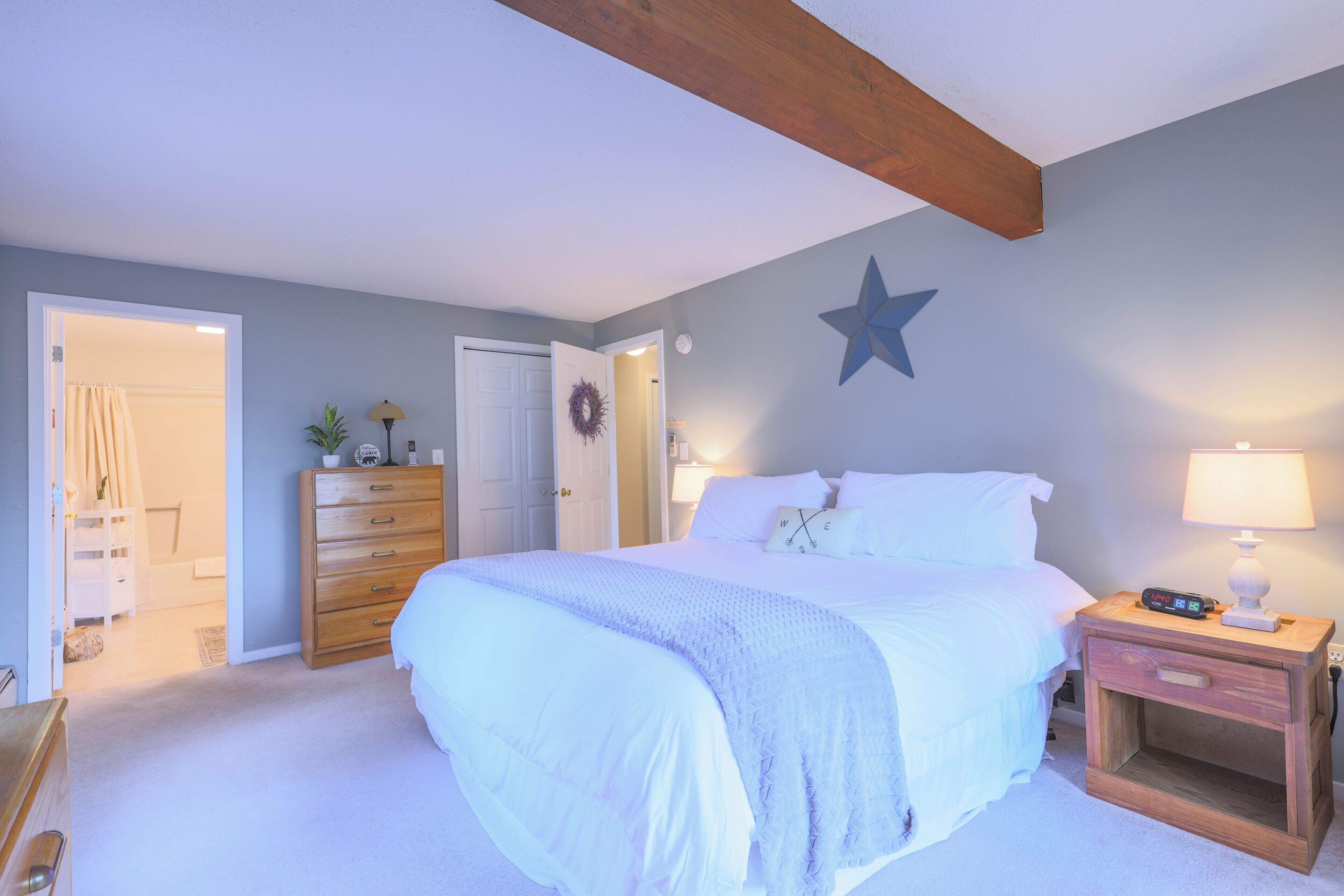 A bedroom with a bed, nightstand, dresser, and a star decoration on the wall.
