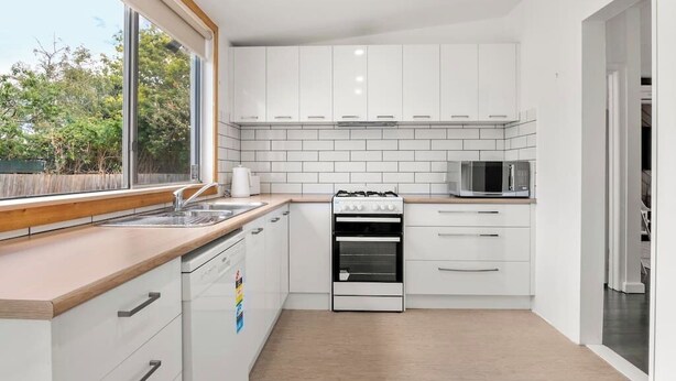 A modern kitchen with white cabinets, a stainless steel sink, a microwave, and a stove. - Bonbeach Beauty: Relaxation Haven in Bonbeach! (Bonbeach)