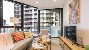 Una sala de estar moderna con sofá, sillón, mesa de centro y mueble para televisión.