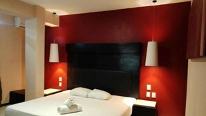 Una habitación de hotel moderna con una cama grande, paredes rojas de acento y dos lámparas de noche.
