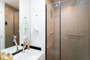 A modern bathroom with a glass-enclosed shower, a large mirror, and a white sink. - On Melo Alves R (São Paulo)