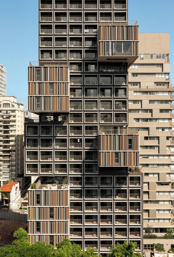 A modern high-rise building with multiple balconies, large windows, and a mix of residential and commercial spaces. - On Melo Alves R (São Paulo)