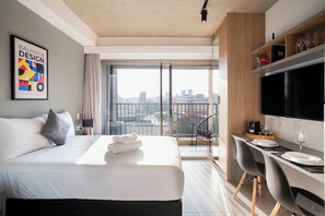 A modern hotel room with a large bed, a desk with chairs, a TV, and a city view. - On Melo Alves R (São Paulo)