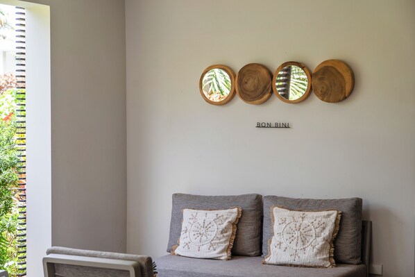Una habitación con un sofá gris, dos almohadones decorativos y tres piezas de arte de madera en la pared.