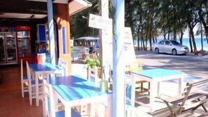 A beachfront restaurant with outdoor seating, a visible menu board, and a view of the ocean. - Pama Resort (Rayong City)