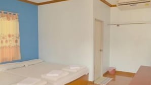 A room with a bed, a small table, a window with curtains, and an air conditioning unit. - Pama Resort (Rayong City)