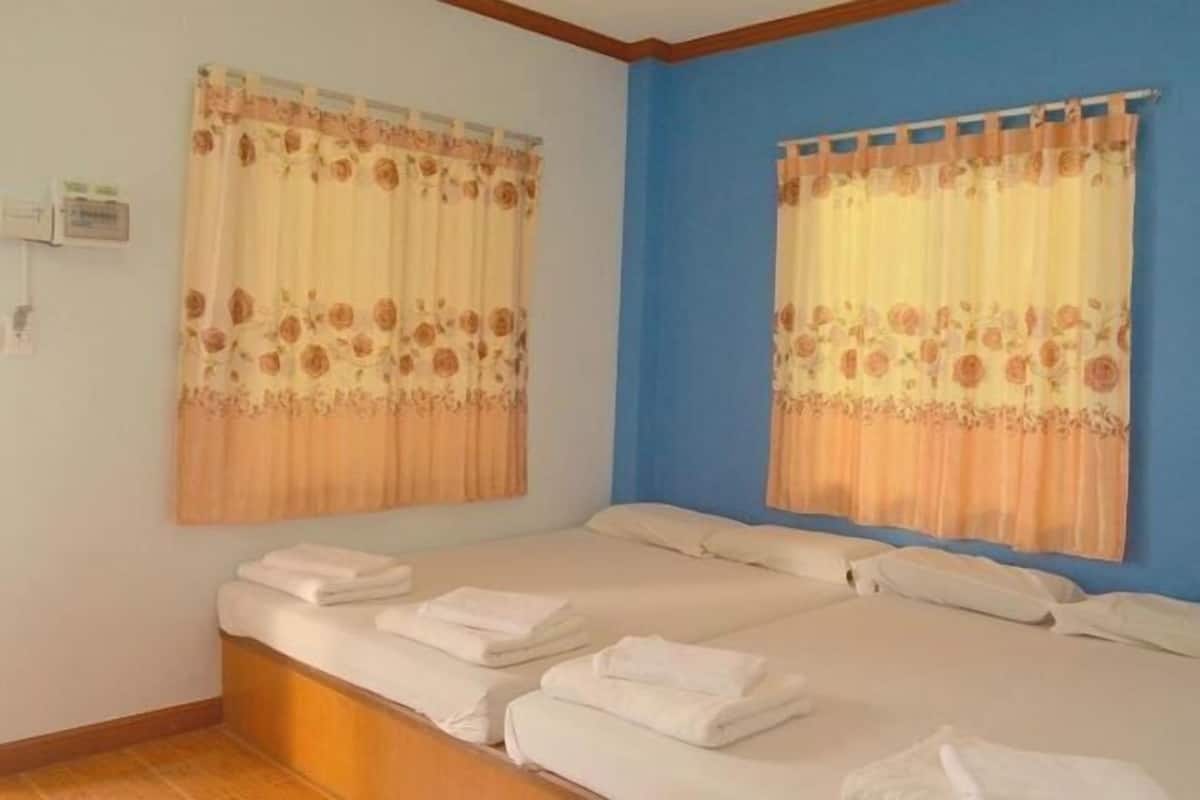 Ein Doppelzimmer mit zwei Betten, blumigen Vorhängen und einer blauen Akzentwand.