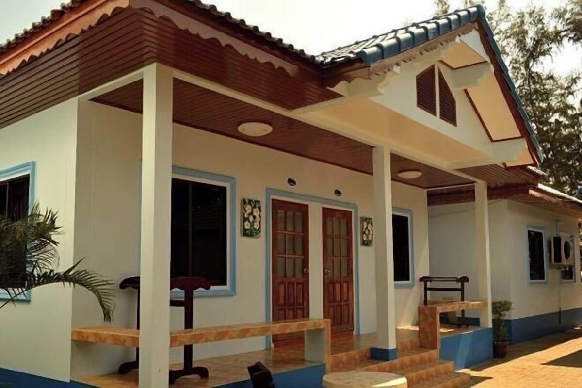 A two-story house with a porch, wooden doors, and a tiled roof.