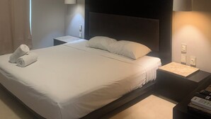 A hotel room with a bed, bedside table, lamp, and ceiling light. - Room with King bed in BLVD HOTEL, fifth avenue (Playa del Carmen)