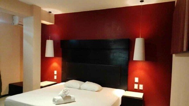 A modern hotel room with a large bed, red accent walls, and two bedside lamps. - Room with King bed in BLVD HOTEL, fifth avenue (Playa del Carmen)