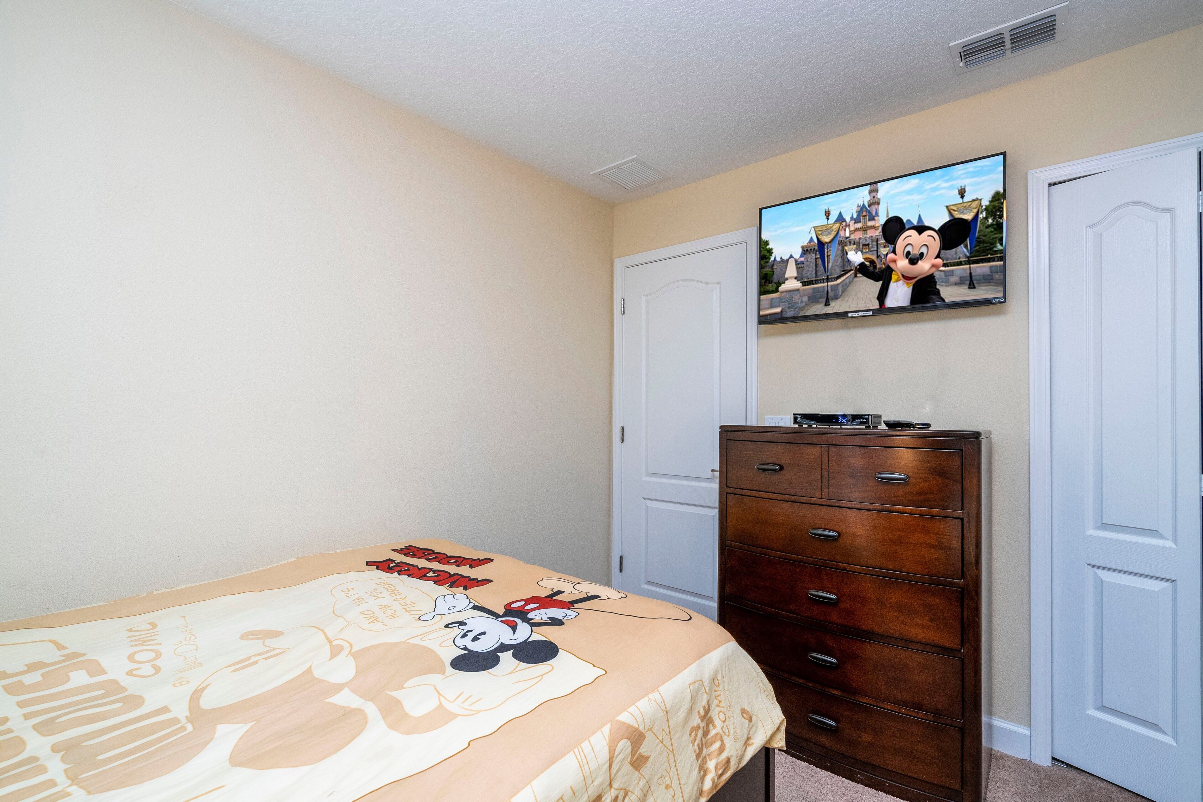 Une chambre à coucher avec un lit, une commode et un téléviseur fixé au mur.