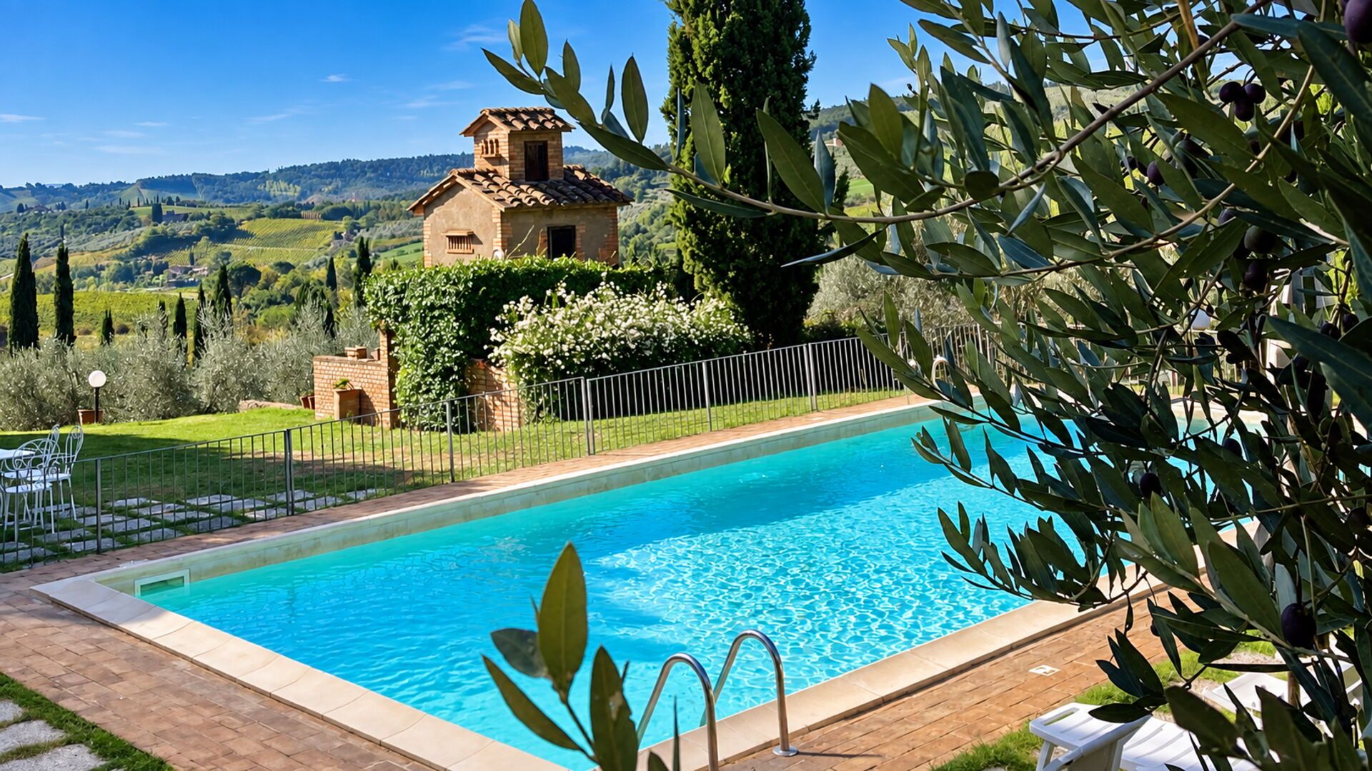 Une piscine avec vue sur un paysage rural, une petite maison et des oliviers.
