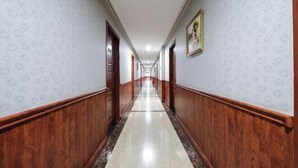 Un largo y estrecho pasillo con paneles de madera y suelo de mármol.
