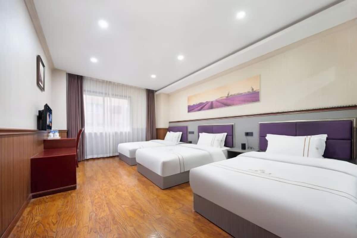 A hotel room with two beds, a desk, and a window with curtains.